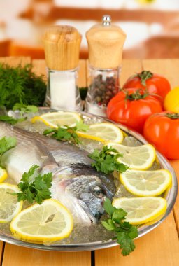 dorado fresco en tajadera con limón y verduras en la mesa de madera