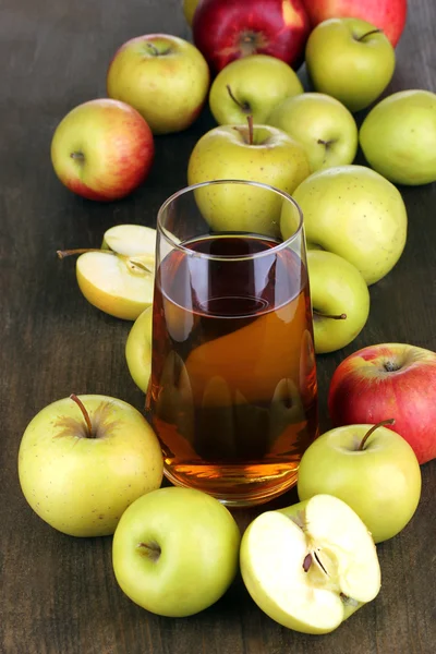 Användbara äppeljuice med äpplen runt på träbord — Stockfoto