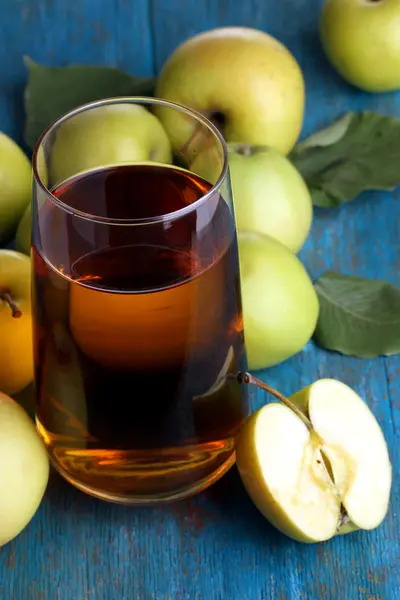 Användbara äppeljuice med äpplen runt på träbord — Stockfoto