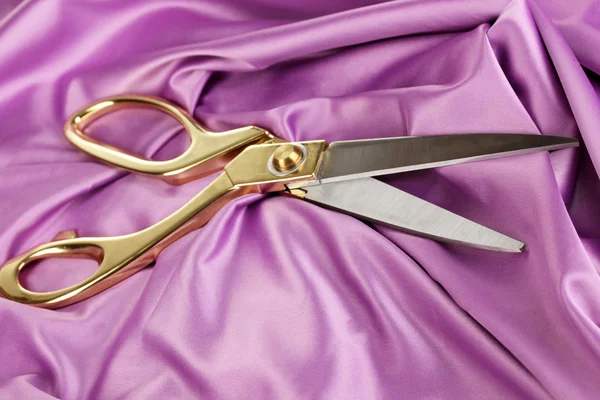 Metal scissors on purple fabric — Stock Photo, Image
