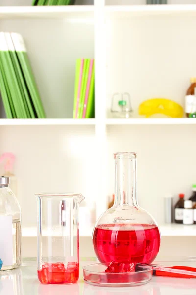 Diferentes cristalería de laboratorio con líquido de color sobre fondo de laboratorio —  Fotos de Stock