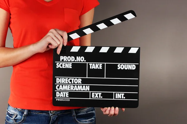 Movie production clapper board in hands on grey background — Stock Photo, Image