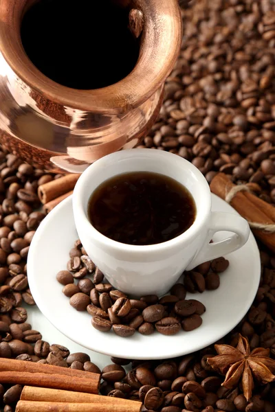 Cup and pot of coffee on coffee beans background — Stock Photo, Image