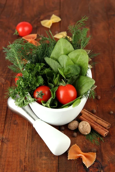 Herbes et épices en mortier céramique, sur fond bois — Photo