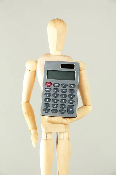 Wooden mannequin with calculator on grey background — Stock Photo, Image