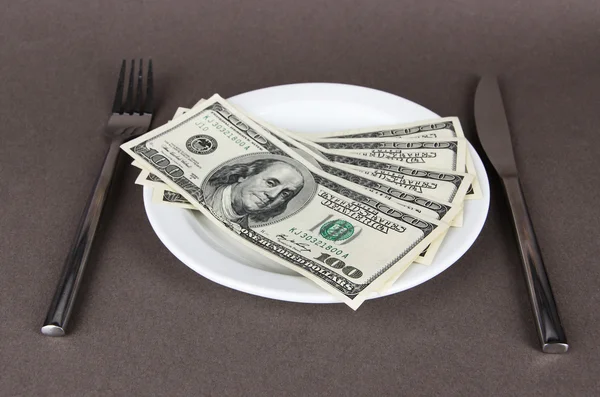 Деньги на тарелке на сером фоне — стоковое фото