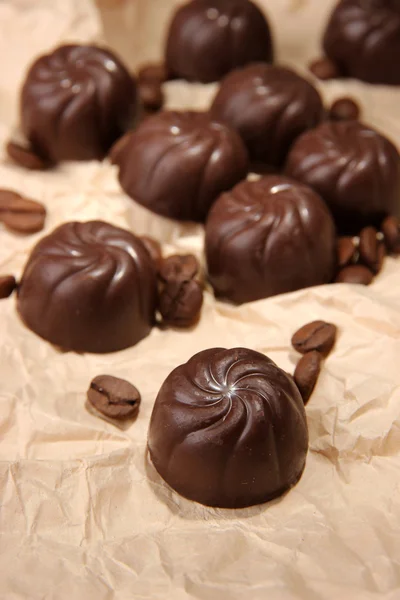 Caramelle al cioccolato e chicchi di caffè, su sfondo di carta beige — Foto Stock