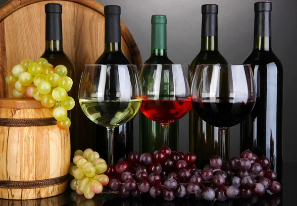 Weinsortiment in Gläsern und Flaschen auf grauem Hintergrund — Stockfoto