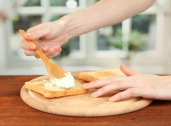 Process of preparing salami rolls on roasted bread ,on bright background: female hand smears cheese cream on roasted bread — Stock Photo, Image