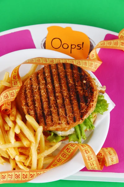 Hamburger, hranolky na desce v měřítku na zeleném pozadí — Stock fotografie