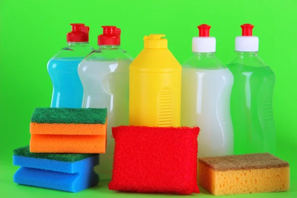 Bottles of dishwashing liquid and sponges on color background — Stock Photo, Image