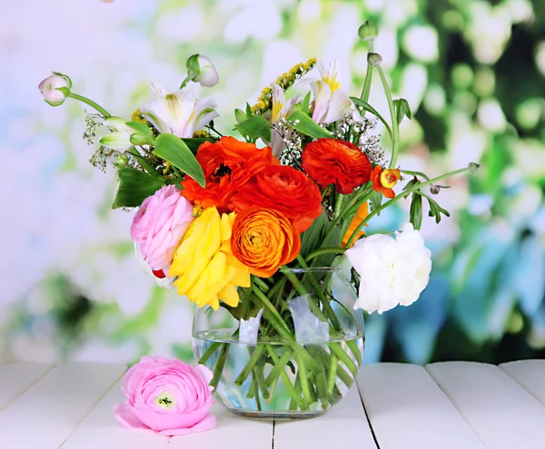 Прекрасные цветы лютик в стеклянной вазе на деревянном столе на естественном фоне — стоковое фото