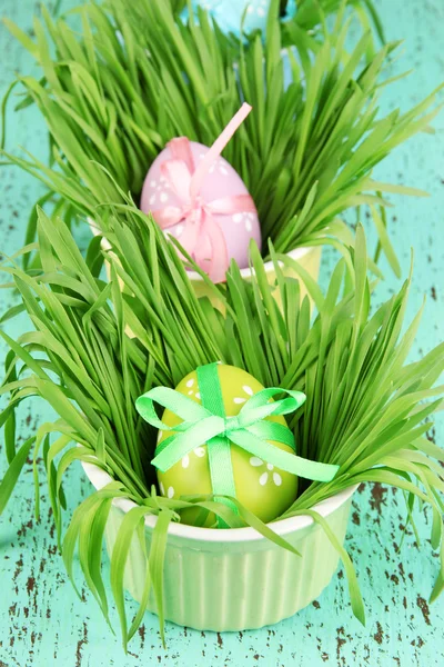 ไข่อีสเตอร์ในถ้วยที่มีหญ้าบนโต๊ะไม้สีเขียว — ภาพถ่ายสต็อก