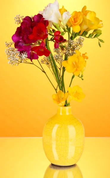 Mooi boeket van fresia's in vaas op oranje achtergrond — Stockfoto