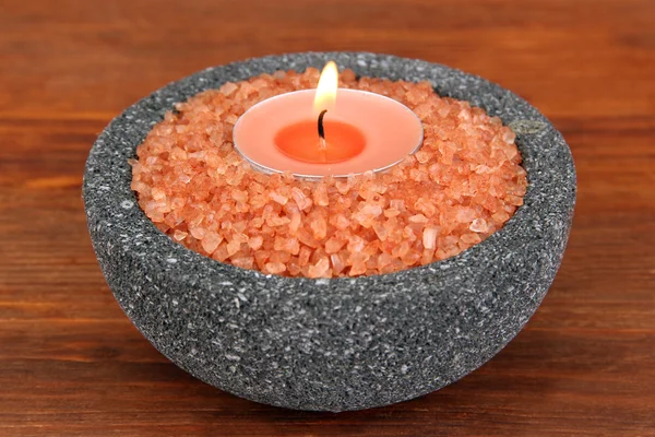 Свеча в каменной чаше с морской солью, на деревянном фоне — стоковое фото