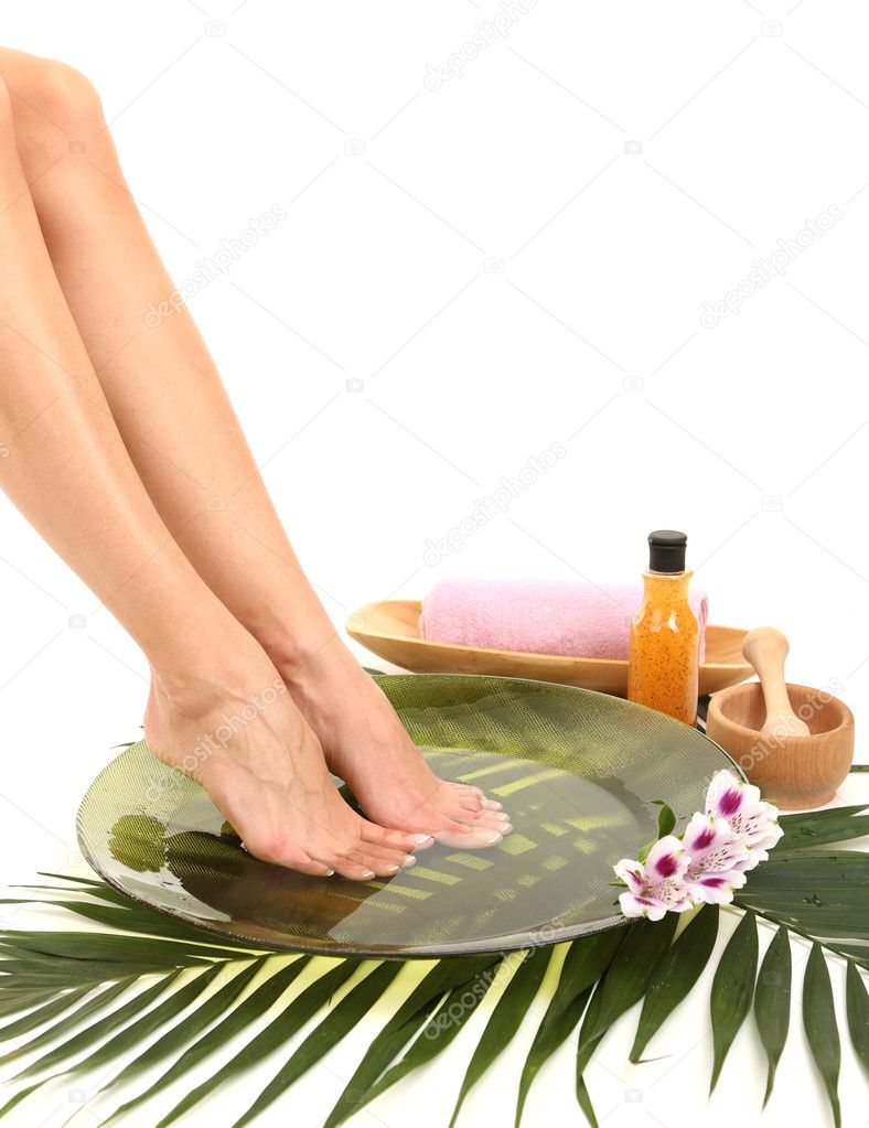 Female feet in spa bowl with water, isolated on white