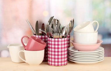 Cups, bowls nd other utensils in metal containers isolated on light background