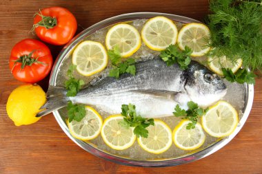 dorado fresco en tajadera con limón y verduras en la mesa de madera
