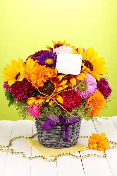 Bellissimo bouquet di fiori luminosi con nota di carta su tavolo di legno su sfondo verde — Foto Stock