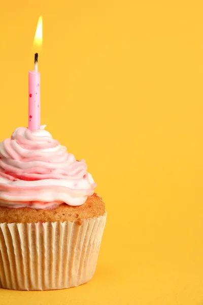 Tasty birthday cupcake with candle, on yellow background — Stock Photo, Image