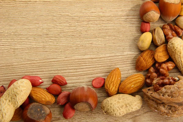 Assortment of tasty nuts on wooden background — Stock Photo, Image