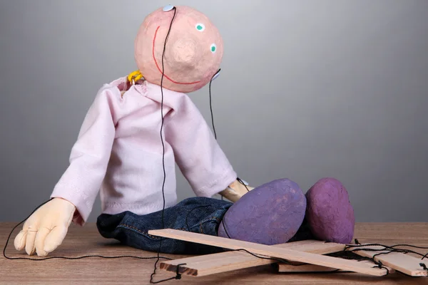 Marionnette en bois assise sur fond gris — Photo