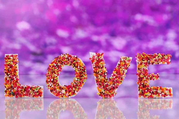 Woord liefde op paarse achtergrond — Stockfoto