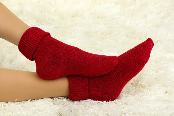 Patas femeninas en calcetines de colores sobre fondo de alfombra blanca — Foto de Stock
