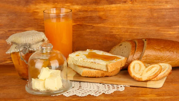 Manteiga no pires de vidro com tampa de vidro e pão fresco, mel no fundo de madeira — Fotografia de Stock