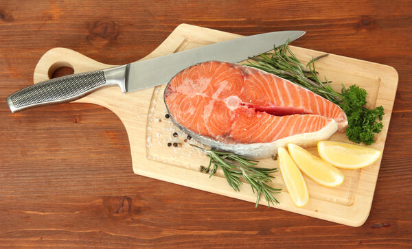 Свежий лосось стейк на доске, на деревянном фоне
