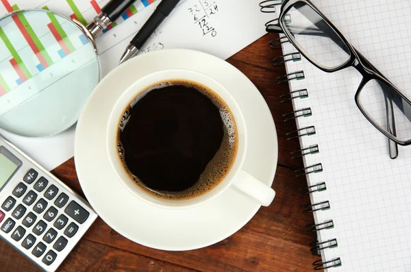 Tasse de café sur la table de travail recouverte de documents close up — Photo