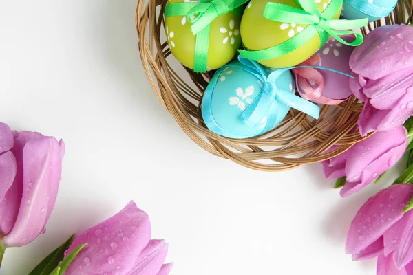 Sepet ve laleler, üzerinde beyaz izole parlak Paskalya yumurtaları — Stok fotoğraf