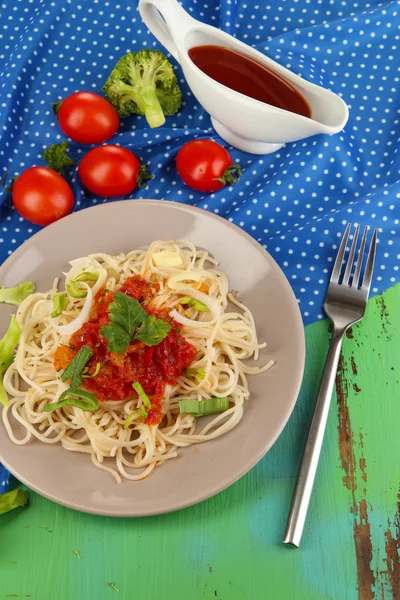 Välsmakande spaghetti med sås och grönsaker på tallriken på träbord närbild — Stockfoto