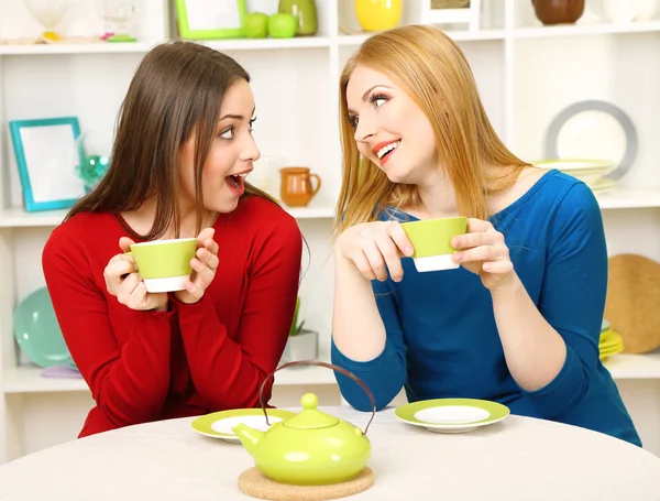 Two girl friends talk and drink tea in kitchen — Stock Photo, Image