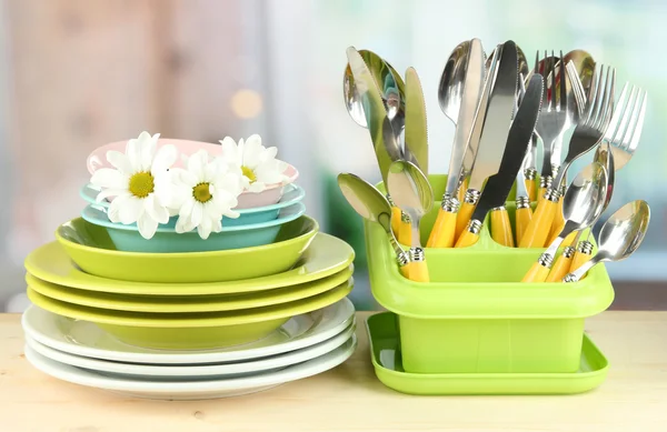 Placas, garfos, facas, colheres e outros utensílios de cozinha sobre fundo brilhante — Fotografia de Stock