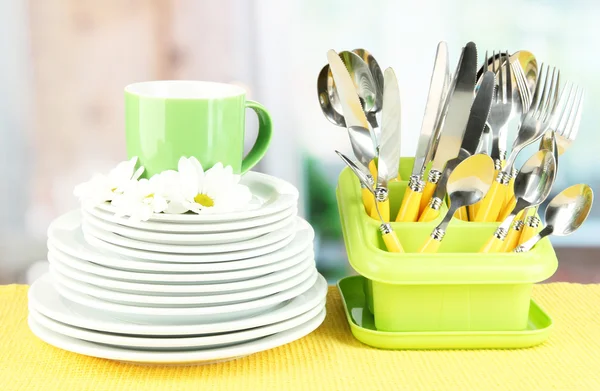 Plader, gafler, knive, skeer og andre køkkenredskaber på farve serviet, på lyse baggrund - Stock-foto