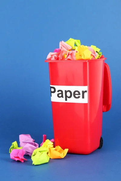 Recycling bin with papers on blue background — Stock Photo, Image