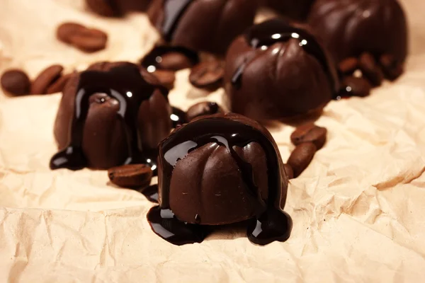 Caramelle al cioccolato e chicchi di caffè, su sfondo di carta beige — Foto Stock