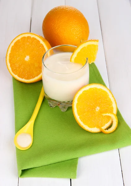 Vaso de yougurt y naranjas sobre naprin sobre fondo de madera —  Fotos de Stock