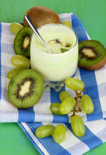 Copo de iogurte com kiwi e uva em guardanapo no fundo verde — Fotografia de Stock