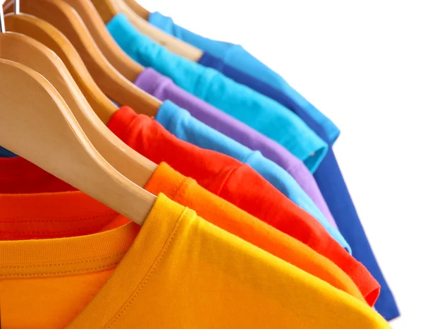 Lots of T-shirts on hangers isolated on white — Stock Photo, Image