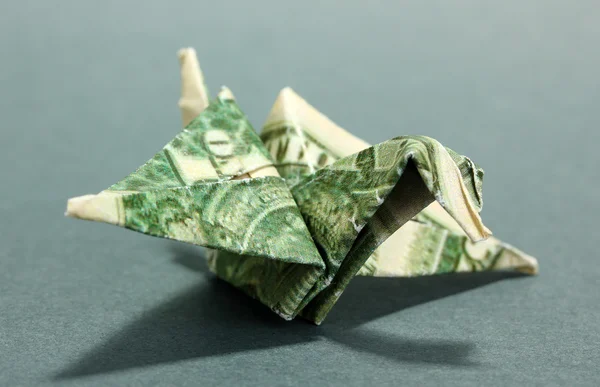 Dollar folded into bird on grey background — Stock Photo, Image
