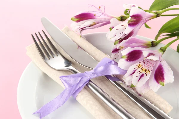 Festive dining table setting with flowers on pink background Stock Photo