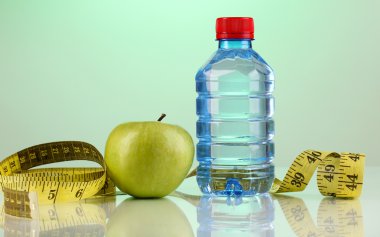 şişe su, elma ve mavi arka plan üzerinde ölçüm bandı