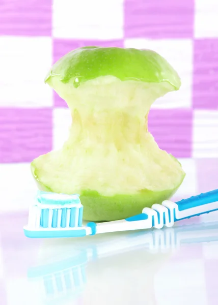 Apple with a toothbrush on shelf in bathroom — Stock Photo, Image