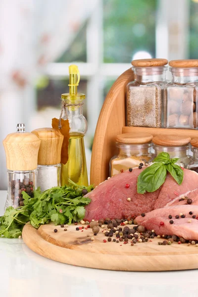 A large piece of pork marinated with herbs, spices and cooking oil on board on white table on window background — Stock Photo, Image