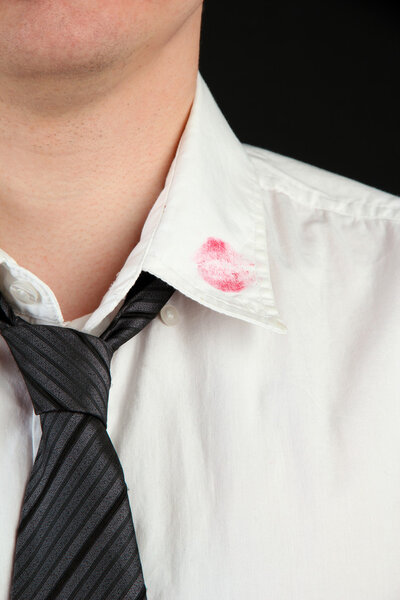 Lipstick kiss on shirt collar of man, isolated on black