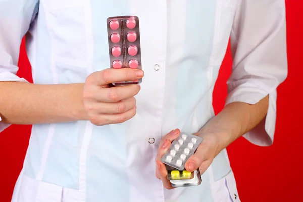 Primer plano de las píldoras de la mano del médico femenino, sobre fondo de color — Foto de Stock