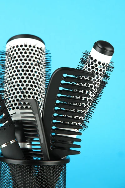 Iron basket with combs and round hair brushes, on color background — Stock Photo, Image