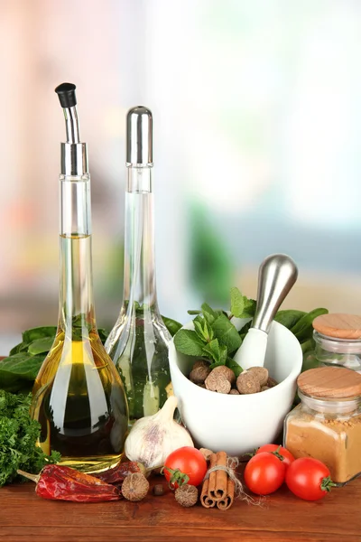 Composición de mortero, botellas con aceite de oliva y vinagre, y hierbas verdes, sobre fondo brillante —  Fotos de Stock